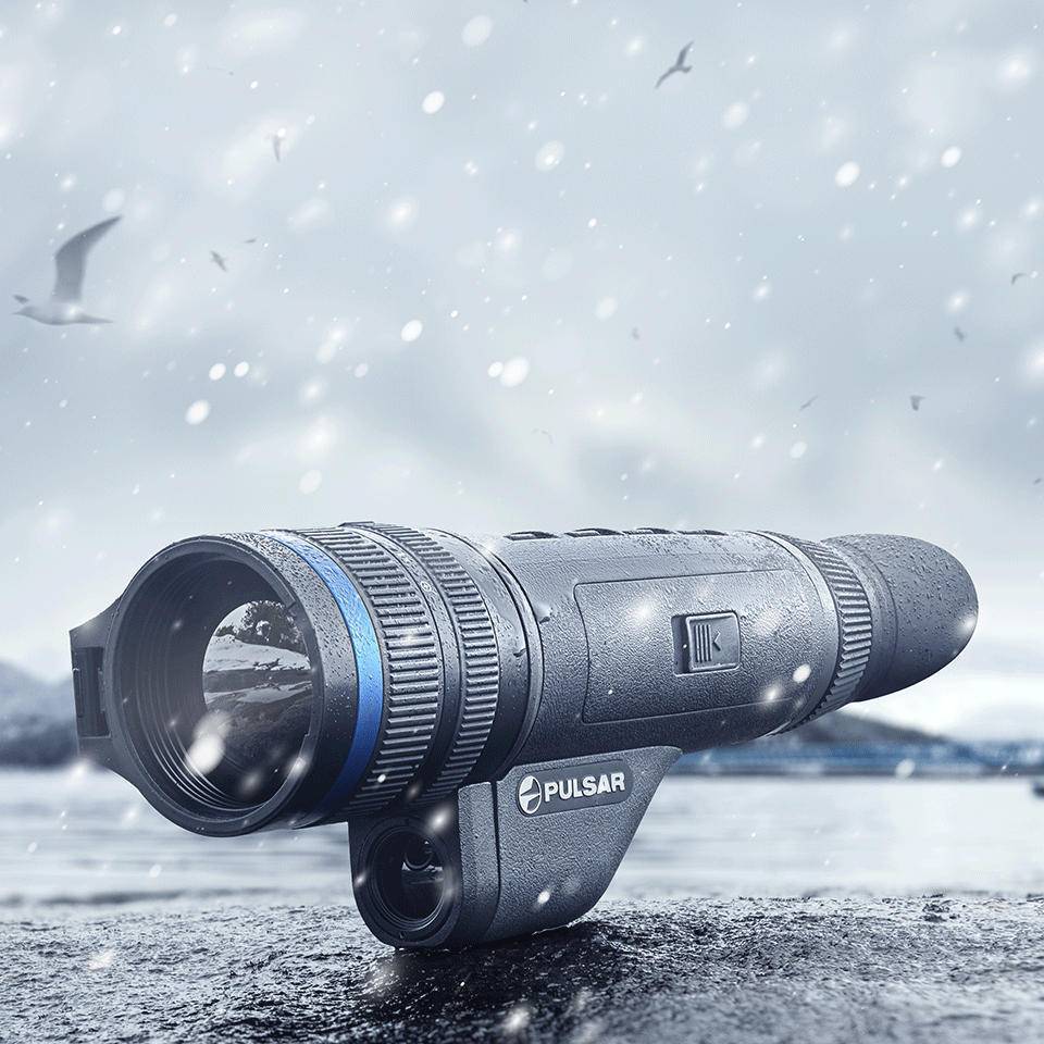 Pulsar Telos XQ35 LRF thermal monocular in snowy outdoor setting, showcasing its weather-resistant build for rugged field use.